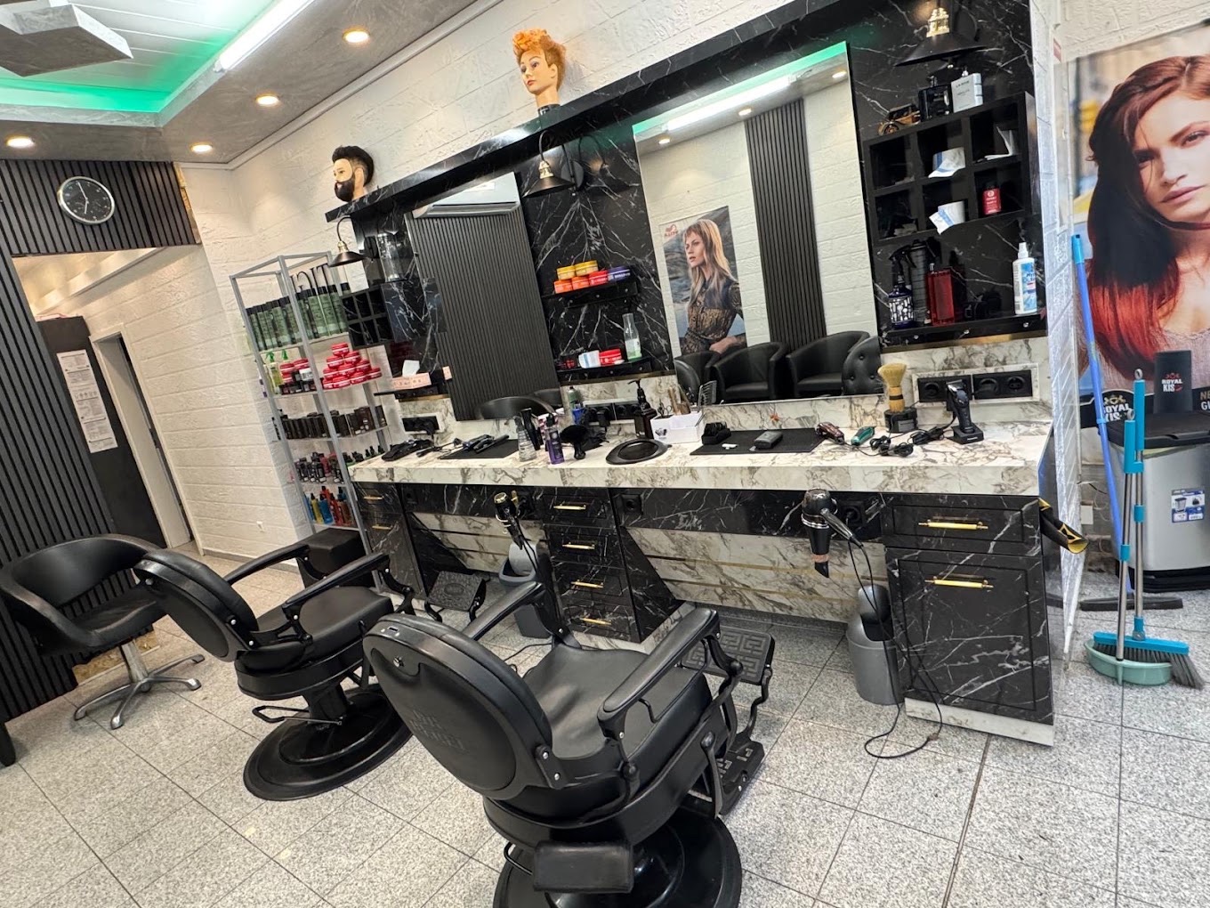 Friseursessel vor Spiegeln mit schwarz-weißer Marmoroptik